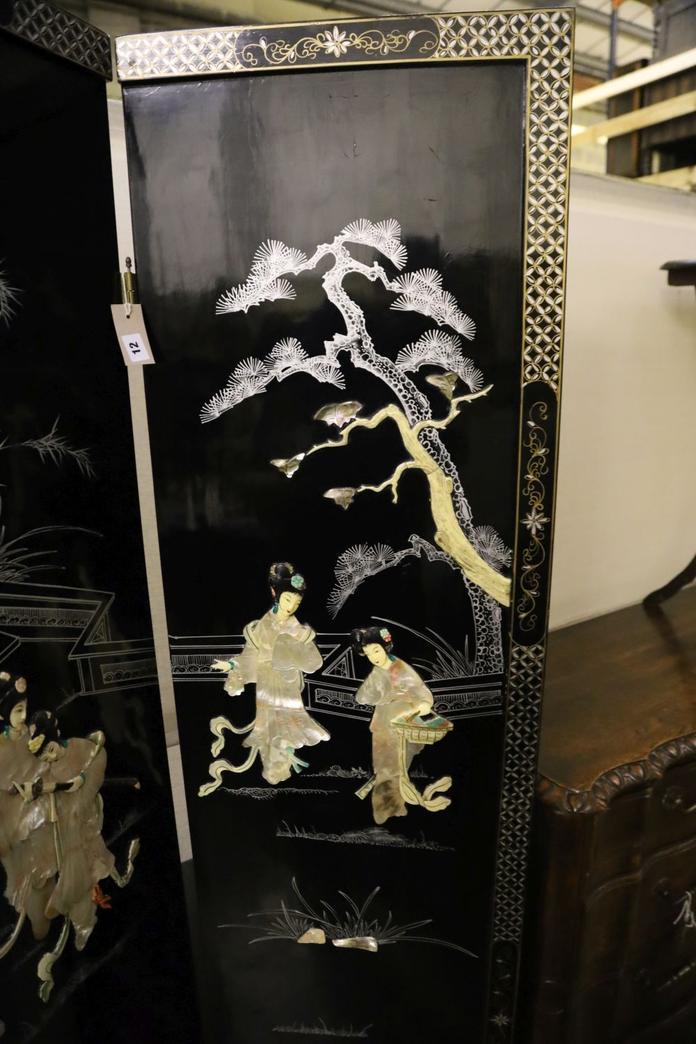 A Japanese black-lacquered and painted four-fold screen with applied decoration of geishas and temple, each panel 46 x 182cm